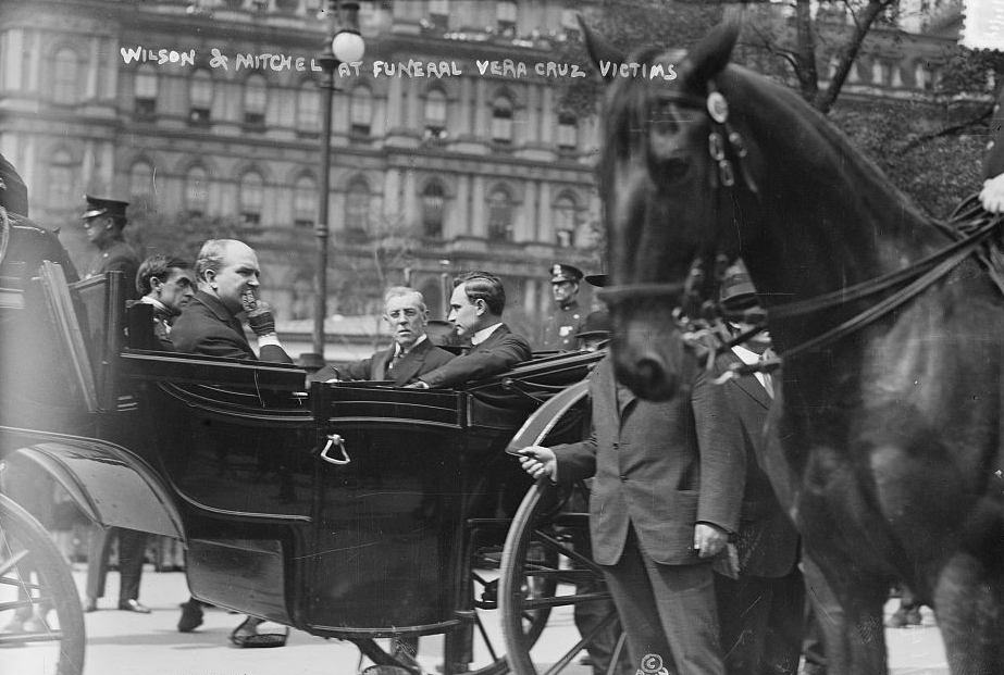 President Woodrow Wilson and three other men ride in a horse-drawn carriage.