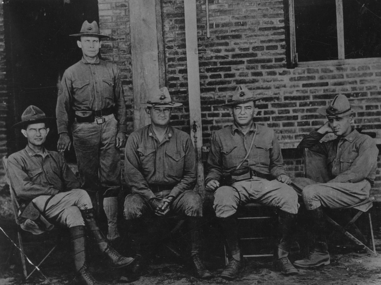 Five uniformed marine officers sit or stand for a photograph.