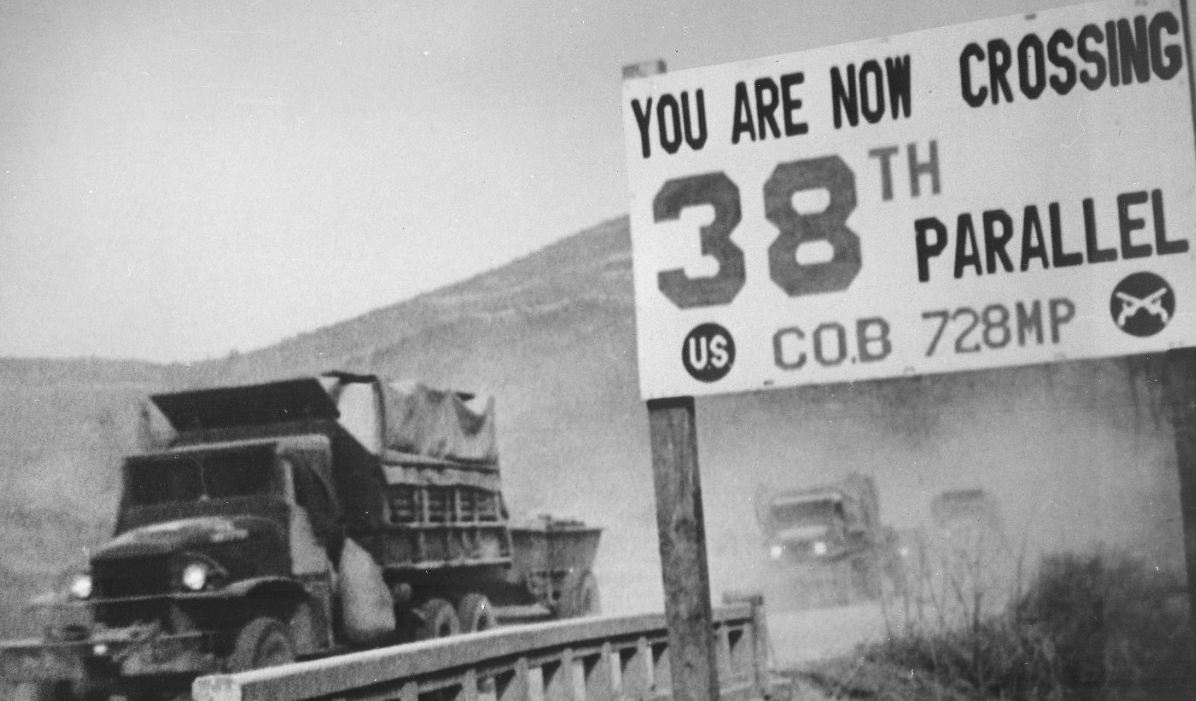 A jeep crossing a bridge next to a sign for the 38th parallel