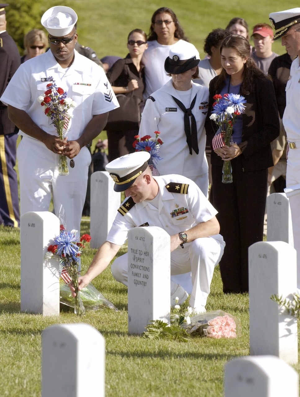 A U.S. Navy lieutenant dropped to one knee and placed flowers on a gravesite