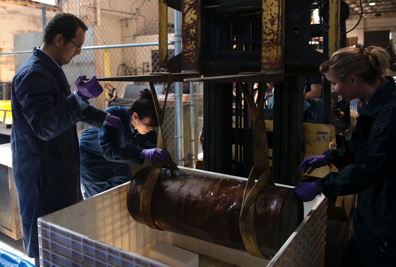 An archaeological team from NHHC prepares to store a section of a late 19th century Howell torpedo in a desalination bin. 