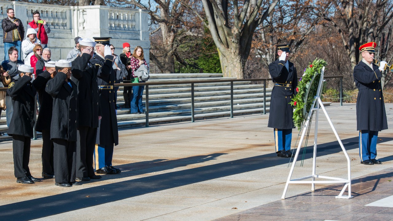 Service members salute a wreath placed in honor of service members killed during the Japanese attack on Pearl Harbor.