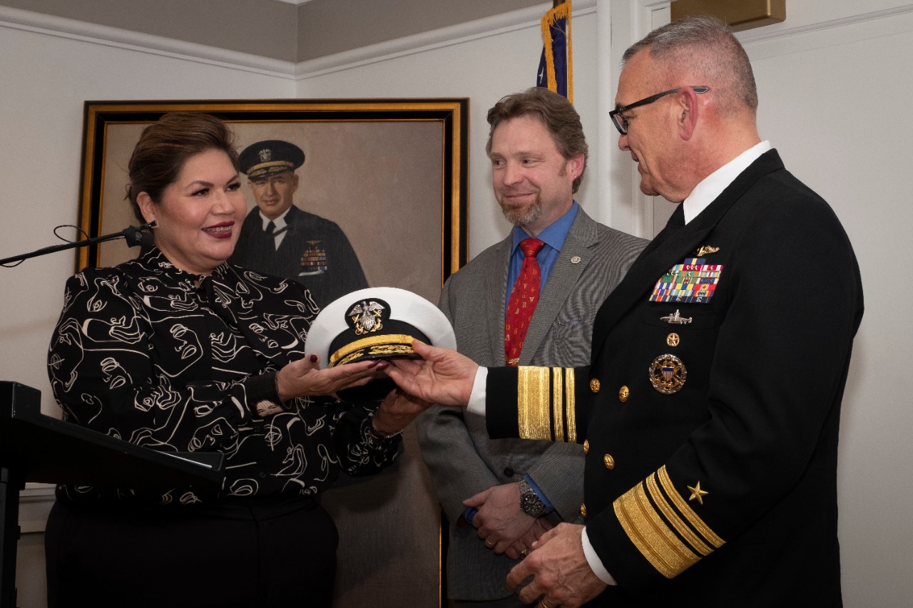 <p>Kimberly Teehee, Cherokee Nation delegate-designate to Congress, presents the U.S. Navy officers crest and cover from the late Adm. Joseph Clark to Deputy Chief of Naval Operations for Information Warfare, Vice Adm. Jeffrey Trussler, during a donation event at The Army and Navy Club (ANC) Washington, D.C., Nov. 12, 2021. Several items cataloging Clark’s accomplishments were collected and donated to the Clark family, the Cherokee Nation, and ANC, recognizing Clark’s many contributions to Naval Aviation throughout his career. (U.S. Navy photo by Mass Communication Specialist 1st Class Torrey W. Lee)</p>
