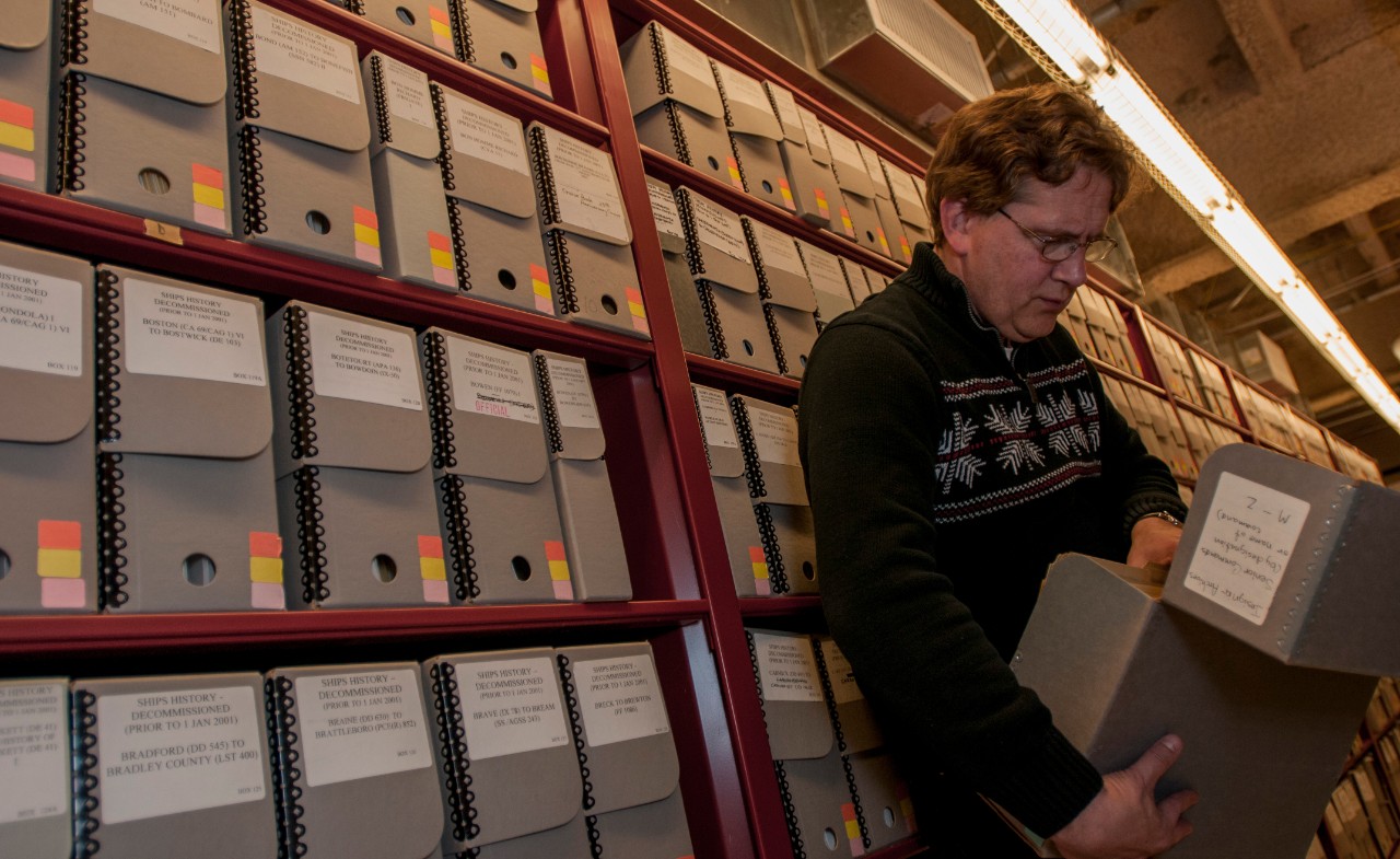 Dale "Joe" Gordon, an archivist at Naval History and Heritage Command, searches archived records for a command operations report (COR) in Naval History and Heritage Command’s Operational Archives. The Chief of Naval Operations-mandated CORs are yearly summaries of command’s operations and major achievements permanently archived for future generations. (U.S. Navy photo by Mass Communication Specialist 2nd Class Eric Lockwood/Released)