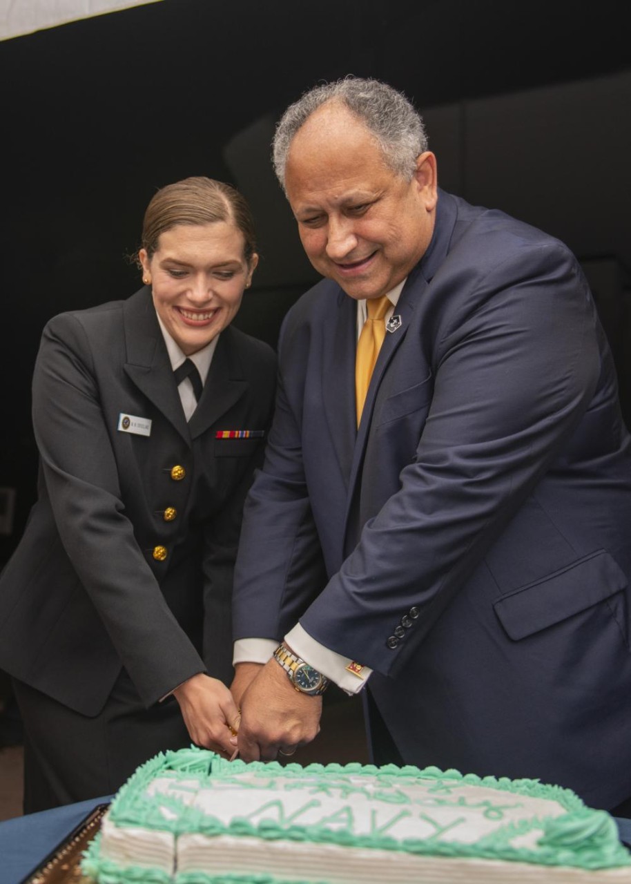 Man and woman in a Navy uniform cutting cake. 