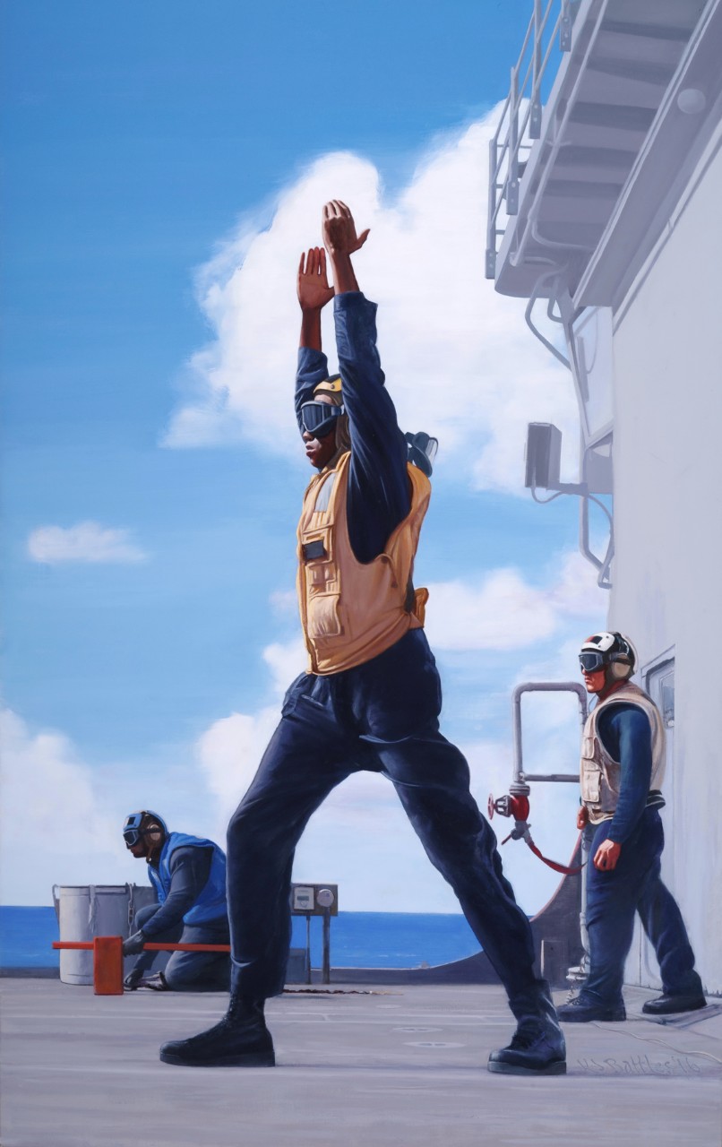 A crewmember on deck is signaling with his arms above his head