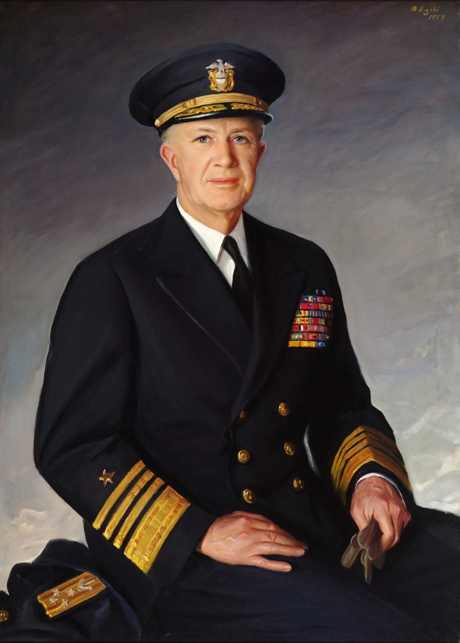 Admiral Robert B Carney is seated and holding gloves in one hand he is wearing dress blues