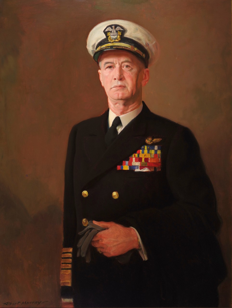Admiral Ernest J King in his dress blues wearing a hat and holding a pair of gloves