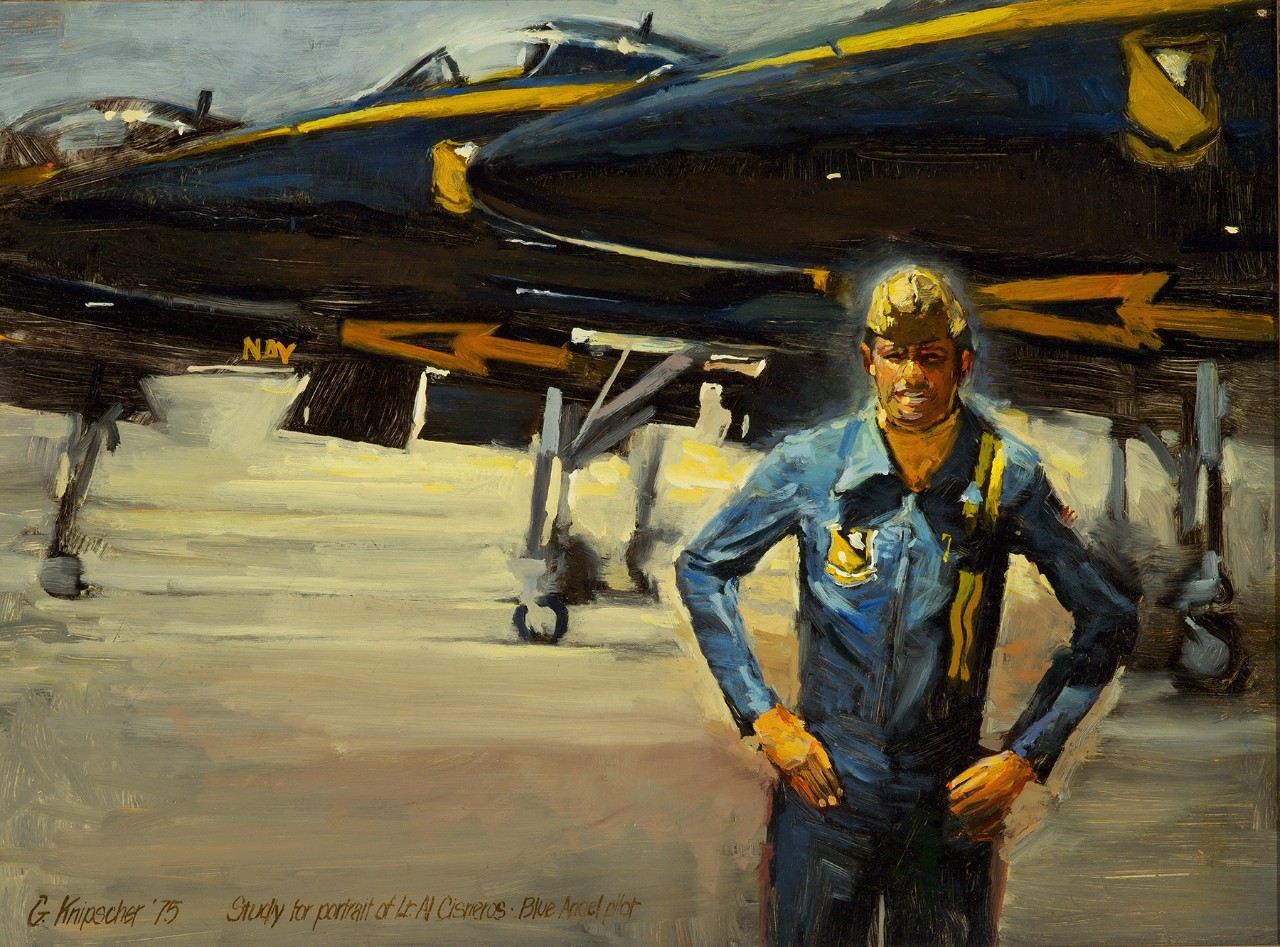 Al Cisneros in a Blue Angels uniform standing in front of Blue Angels planes.