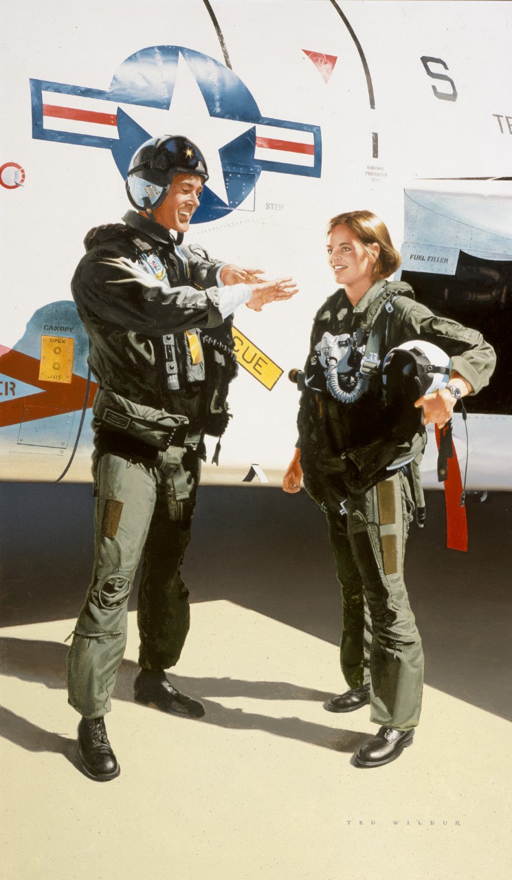 Two pilots a man and a woman stand in front of a trainer plane