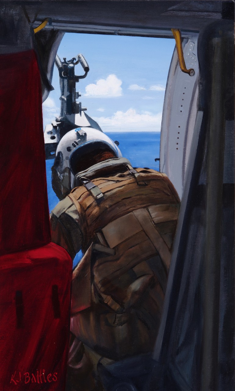 A crewman is looking down out the hatch of a helicopter