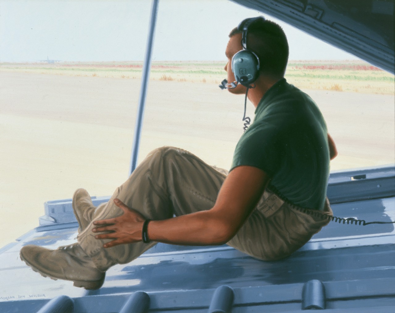 A marine sits on the ramp of a C-130 airplane with his communications gear on