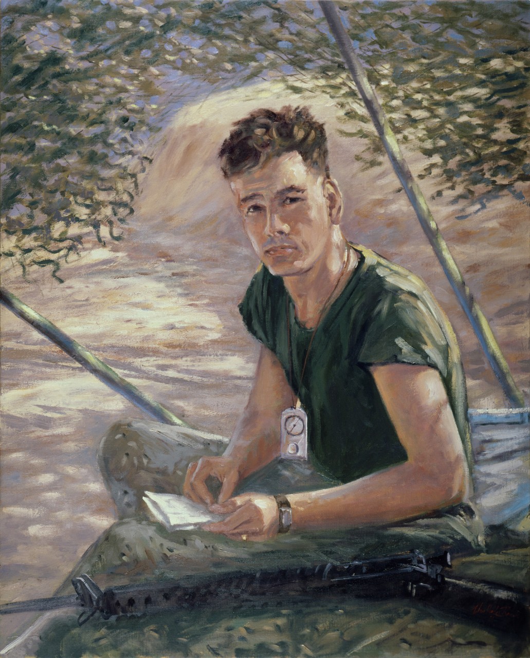 A marine under camouflage netting writing a letter 