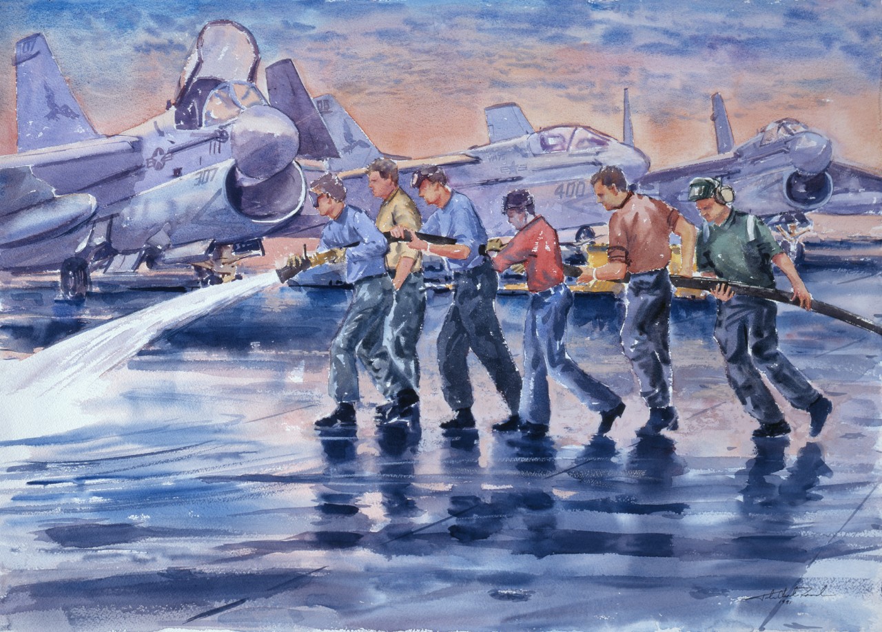 Crewmen using a water hose to wash the deck of an aircraft carrier