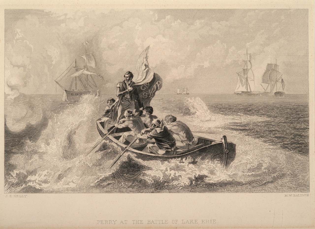 A man holding a flag stands in a boat as it battles waves, there is a ship battle is in the background
