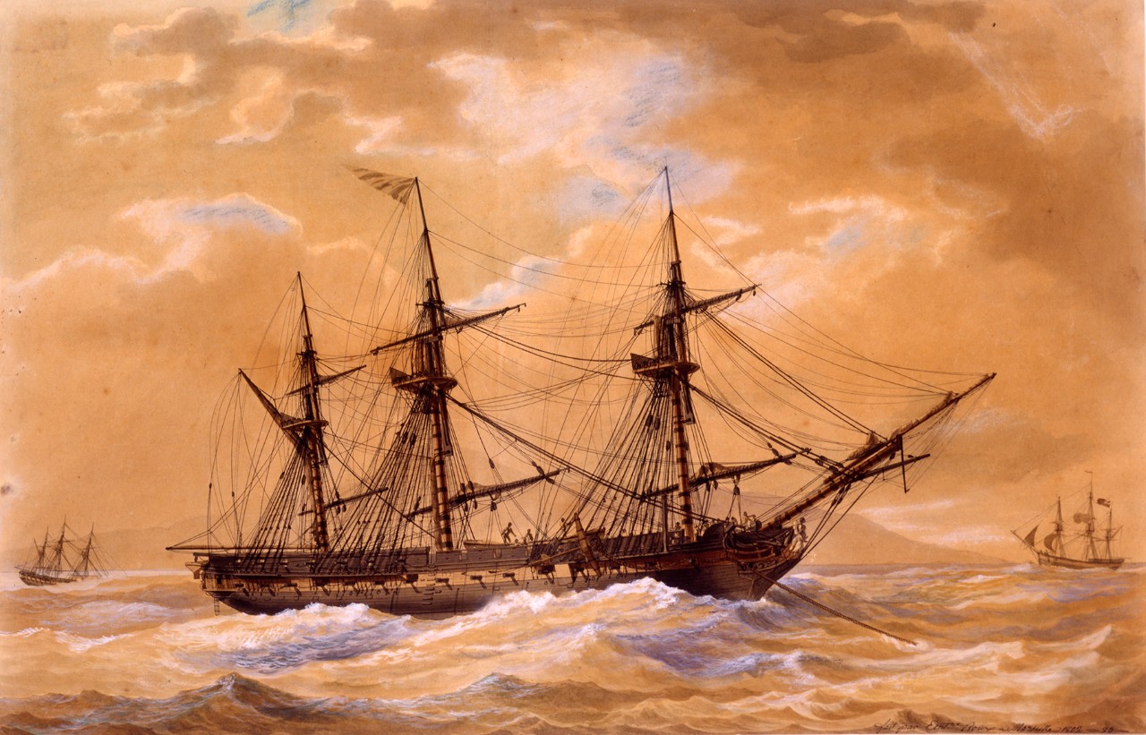 A frigate is anchored in choppy seas with two other ships in the far background