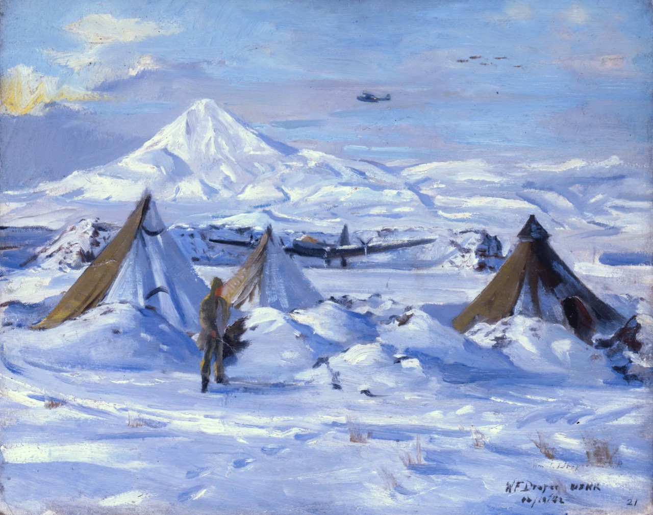 A man stands in front of three snow covered tents 