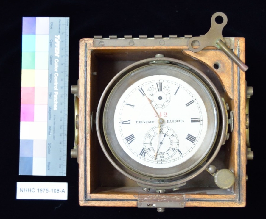 One chronometer recovered from U-505. The face and frame are 5” in diameter. The face bears the number 242 in red, with roman numerals around the border to mark the time, a seconds dial with black hand and inscribed “Ulysse Nardin, Locle, Suisse, Grand Prix Paris,” and the makers name F. Dencker of Hamburg across the center. The winding indicator at the top center is inscribed “down bas up haut.” 