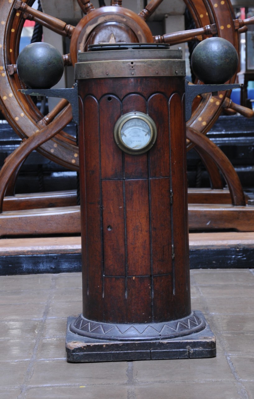 Wood stand with iron orbs on either side and a compass at the top