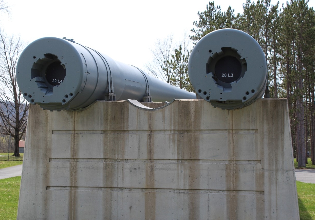 Close-up view of the open breeches of two 14-inch/45 caliber gun barrels from USS Pennsylvania (BB-38). The bore of each barrel is sealed by a black plug. The gun on the left is labeled 22L4. The gun on teh right is labeled 28L3. 