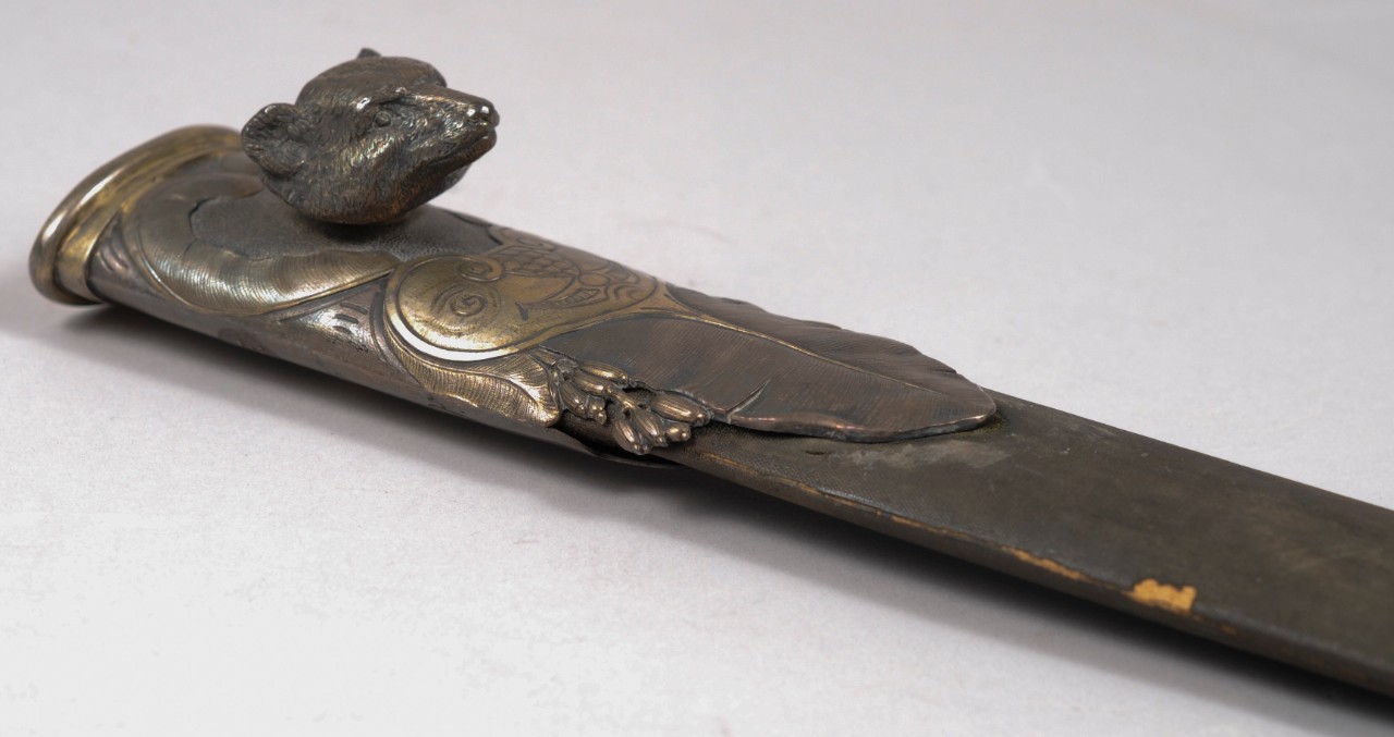 Silver throat of scabbard. Carved bear head projects from throat.