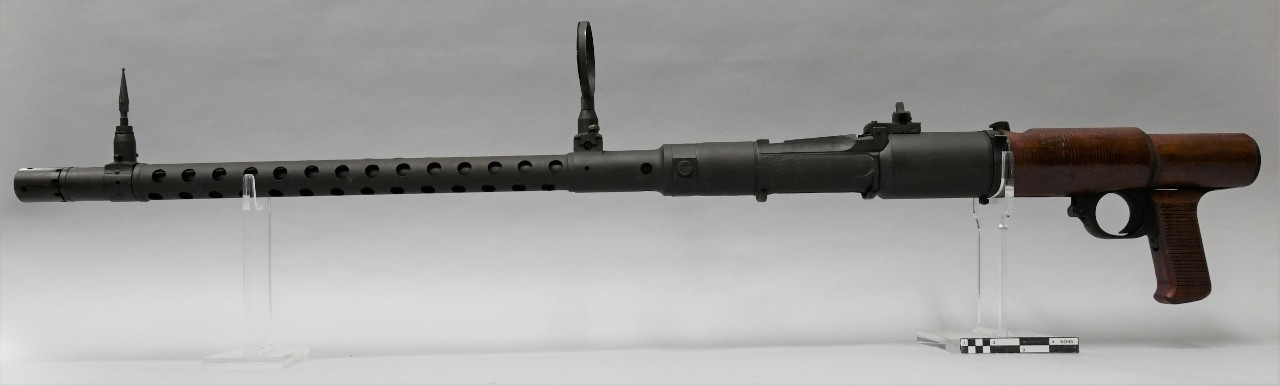Left side of a Japanese Type 98/Type 1 aircraft machine gun. The gun has a long metal tubular barrel. The rear of the receiver and pisotl grip have brown wood covers.