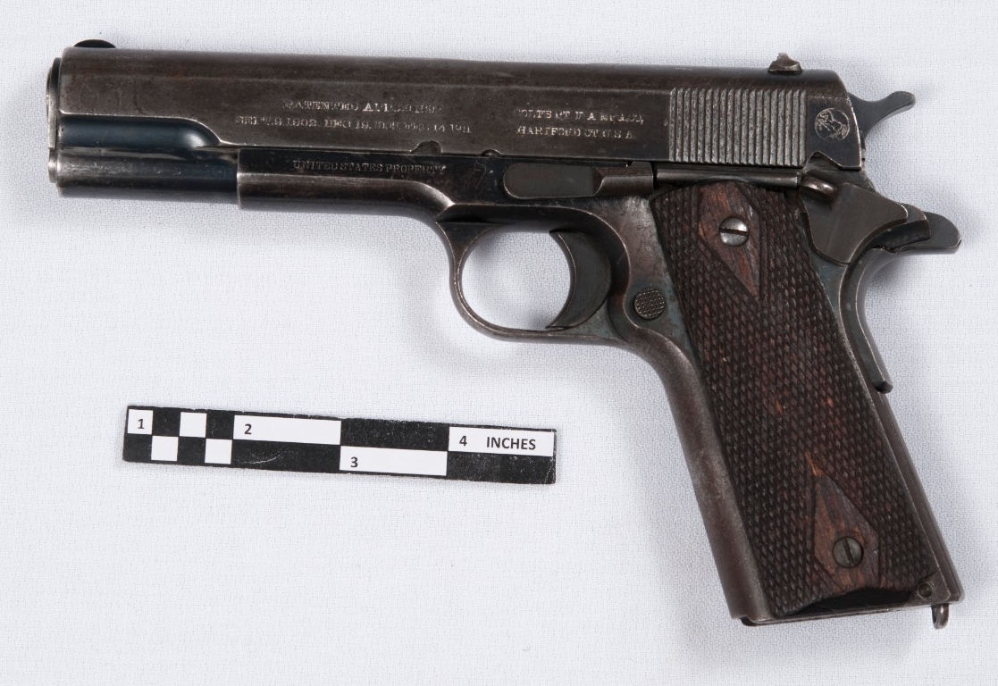 <p>Reverse view of M1911 Navy pistol. .45 caliber pistol fed from 7-a 7-round detachable box magazine housed in the grip. Finish heavily worn from use. Checkered brown plastic grip. The reverse slide is marked “Patented Apr. 20, 1897/Sept. 9, 1902. Dec. 19, 1905. Feb. 14, 1911” and “Colt’s Pt. F.A. Mfg. Co./Hartford Ct U.S.A.” The frame is marked “United States Property.”</p>
