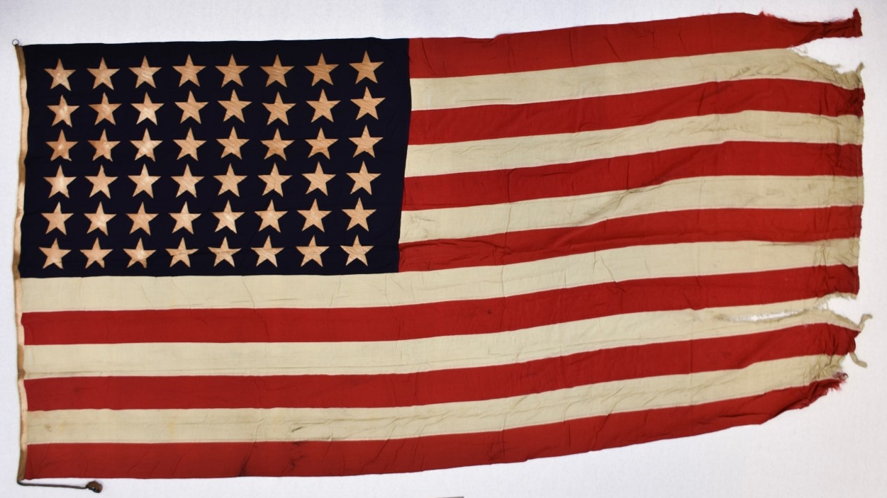 One forty-eight-star national ensign from the light aircraft carrier USS Cowpens (CVL-25). The flag is cotton, of sewn construction and rectangular in shape. Seven alternating horizontal stripes of red and white are joined to a blue canton in the...