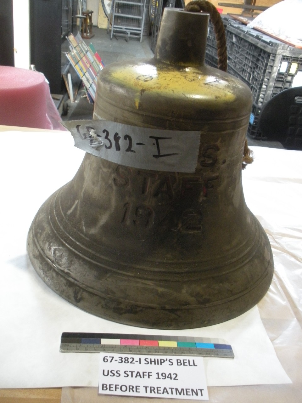 Ship's bell from USS Staff. Bell is covered in dust and has a piece of duct tape attached to it.  