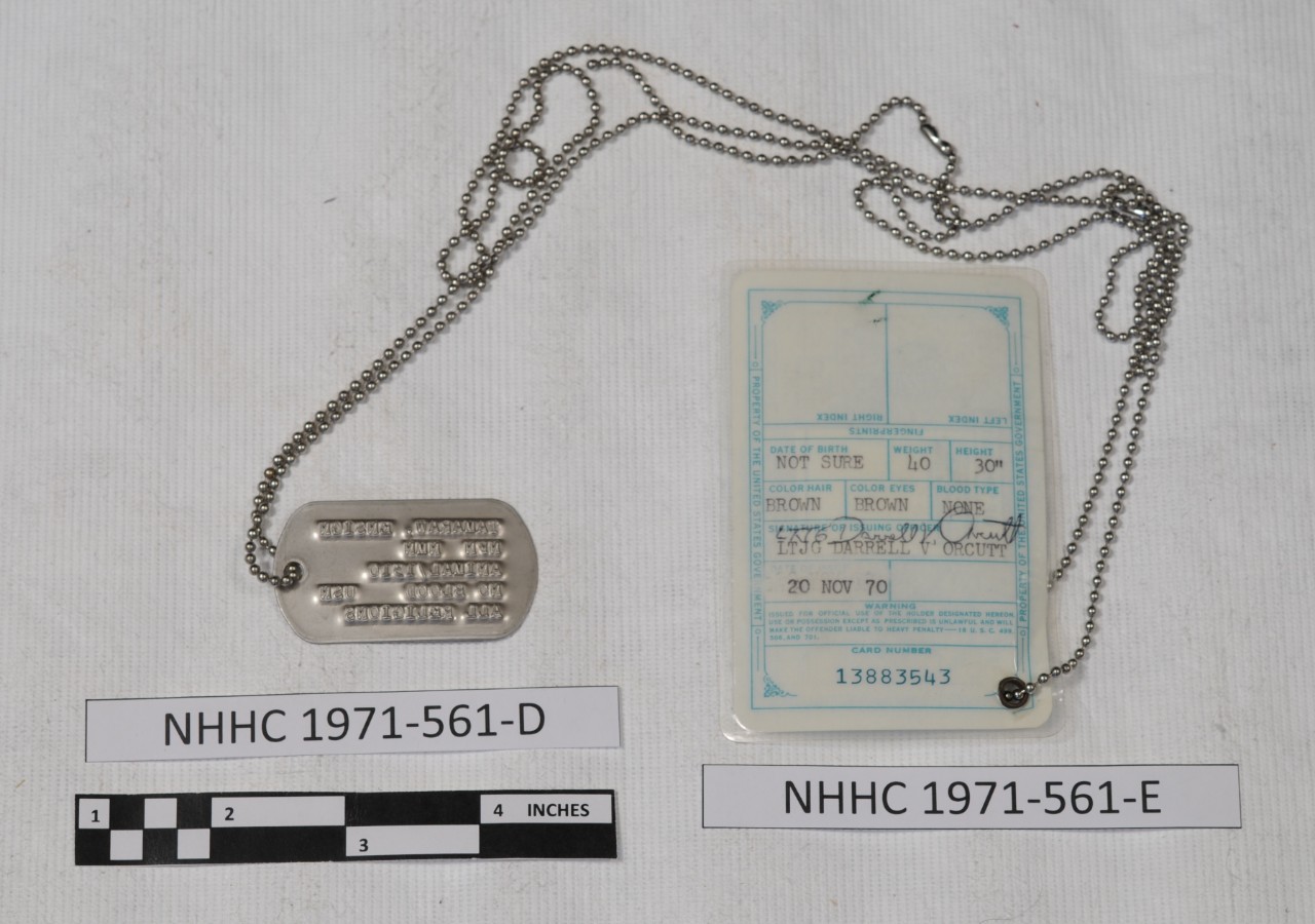 <p>One metal dog tag. The tag is rectangular in shape with rounded ends. One laminated photo identification card. The print and design on the card are in light green. The reverse carries the following information: Date of Birth NOT SURE, Weight 40, Height 30&quot;, Color Hair BROWN, Blood Type NONE, Signature of Issuing Officer LTJG DARRELL V. ORCUTT, Date of Issue 20 NOV 70, Card Number 13883543.</p>
