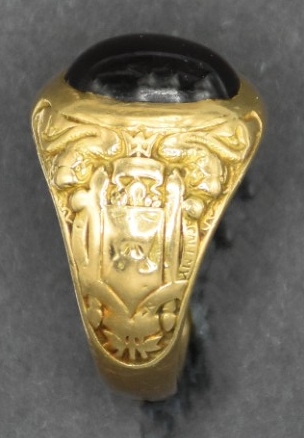 Obverse view of a US Naval Academy midshipman class ring from the class of 1923. Oval purple colored stone set in gold.    