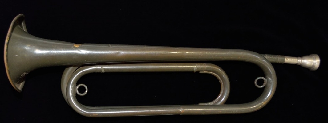 One military-issued service bugle. Brass or copper alloy body painted gray. The body has a double twist shape and a white metal mouthpiece. The bell is stamped “BUGLECRAFT INC./L.I. City, N.Y./U.S.” 