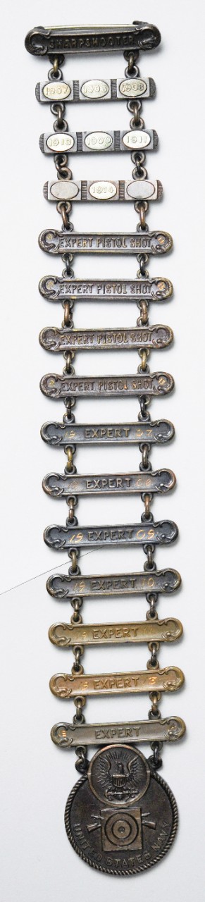 Navy marskmanship badges awarded to Carl T. Osburn for expert in pistol and rifle from 1906 to 1914. 