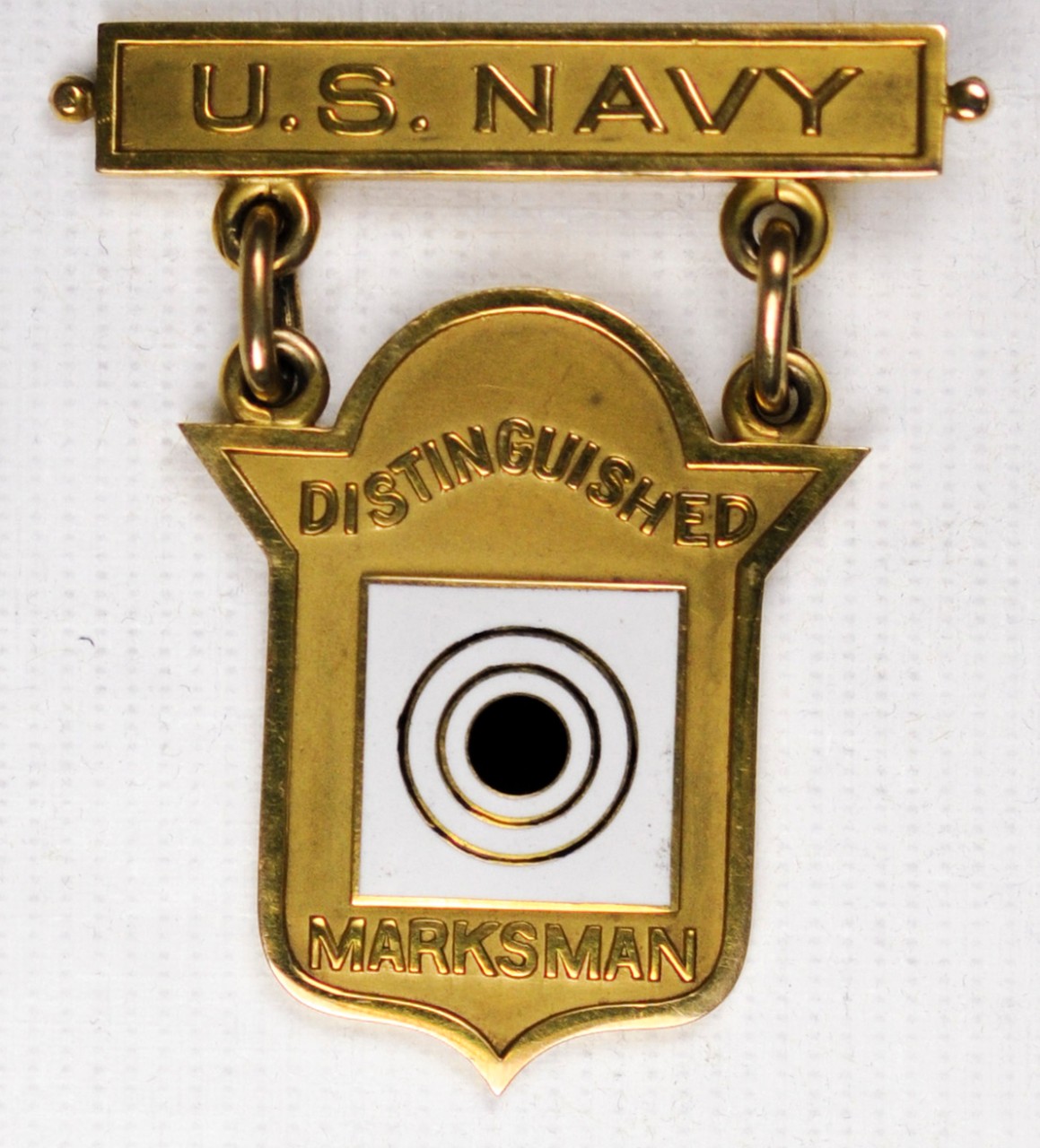 Distinguished Marksman Badge of Carl T OSburn Obverse White and black target in center of gold shield shaped planchette with gold pin and clasp tab