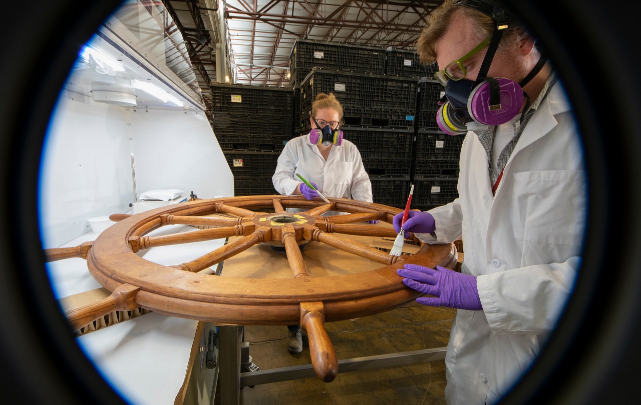 two conservators restoring the wheel of Brandywine