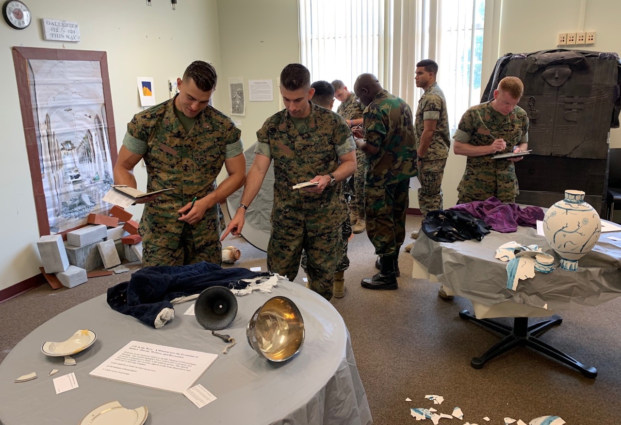 Marines around table looking at artifacts.