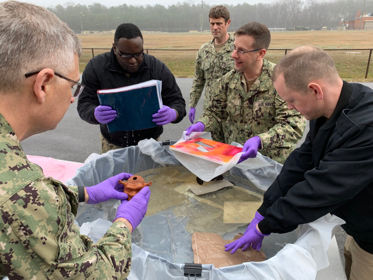 Marines and Sailors reviewing water-damaged sample artifacts.
