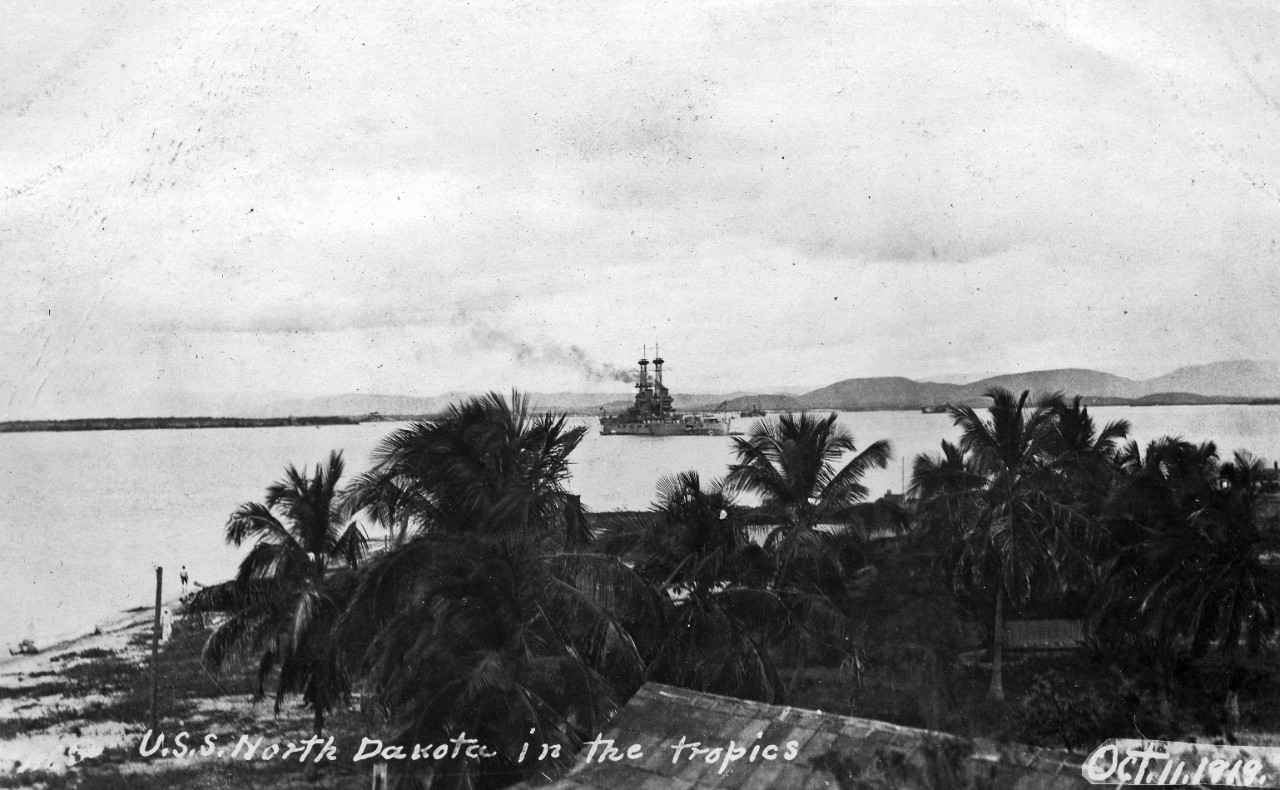 Scrapbook containing approximately 150 postcards related to battleship USS North Dakota (BB-29), circa 1920s, transferred by Naval Hospital, Portsmouth, NH. Many of these postcards appear to be mass produced. Large number of scenes ashore at Guantanamo Bay, Cuba, including firing range, and showing bent 4” gun of USS Monongahela on display; other scenes ashore in Europe including Spain, Greece, Gibraltar, Turkey, Italy. Explosion of motor on board North Dakota’s motor sailor launch at Annapolis in 1920. Casket containing body of Italian Ambassador to the United States Vincenzo Macchi di Cellere being hoisted on board North Dakota at Hampton Roads, Virginia, November 1919. Boxing scenes with Jack Dempsey versus Jess Willard. Other ships seen include USS Connecticut (BB-18), USS South Carolina (BB-26), USS Oklahoma (BB-37), USS Florida (BB-30), USS Utah (BB-31), USS Mississippi (BB-23), USS Minnesota (BB-22), USS Pennsylvania (BB-38), USS Michigan (BB-27), USS Delaware (BB-28), USS New York (BB-34), USS Texas (BB-35), USS New Mexico (BB-40), USS Wyoming (BB-32), USS Nevada (BB-36), USS New Hampshire (BB-25), USS Louisiana (BB-19), USS Kansas (BB-21), USS Sharkey (DD-281), as well as a few Italian and British warships.