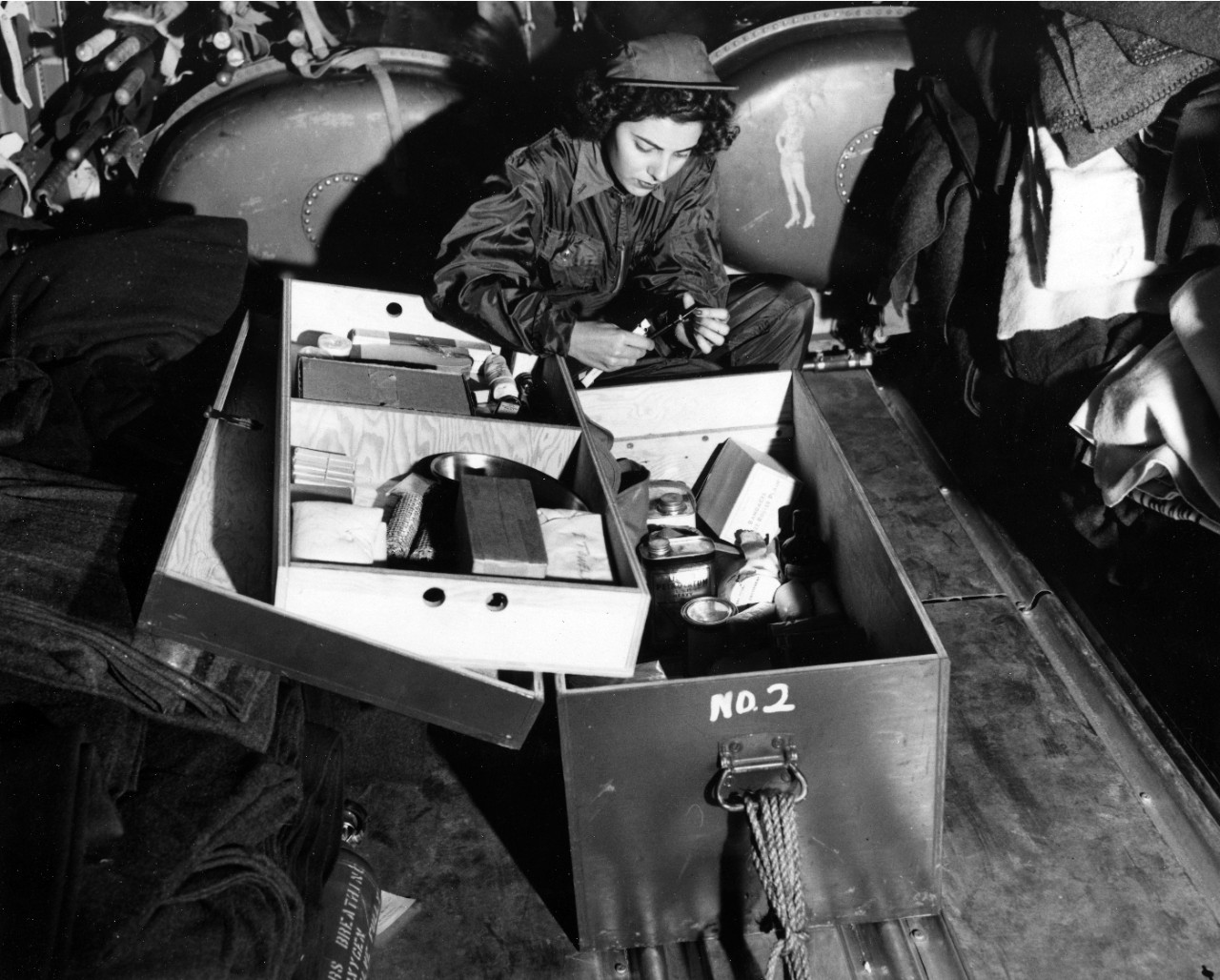 Checking over her kit of medical supplies is Ensign Jane Kendiegh, USNR, a Navy flight nurse, as she flies from a base in the Marianas to the Iwo Jima battleground, aboard a big Navy transport plane, March 6, 1945. Miss Kendiegh was the first navy flight nurse to set foot on a battlefield. 