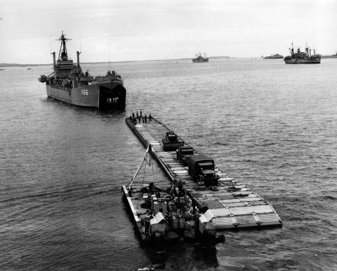 Collection of 24 images related to the May 1965 initial landings at Chu Lai, South Vietnam. Specific imagery consists of amphibious landing craft (large groupings at sea and unloading at the shore), helicopters carrying vehicles ashore, aerials of Chu Lai, unloading vehicles and cargo from USS Washtenaw County (LST-1166) and USS Vernon County (LST-1161), and USS Henrico (APA-45) off shore. 