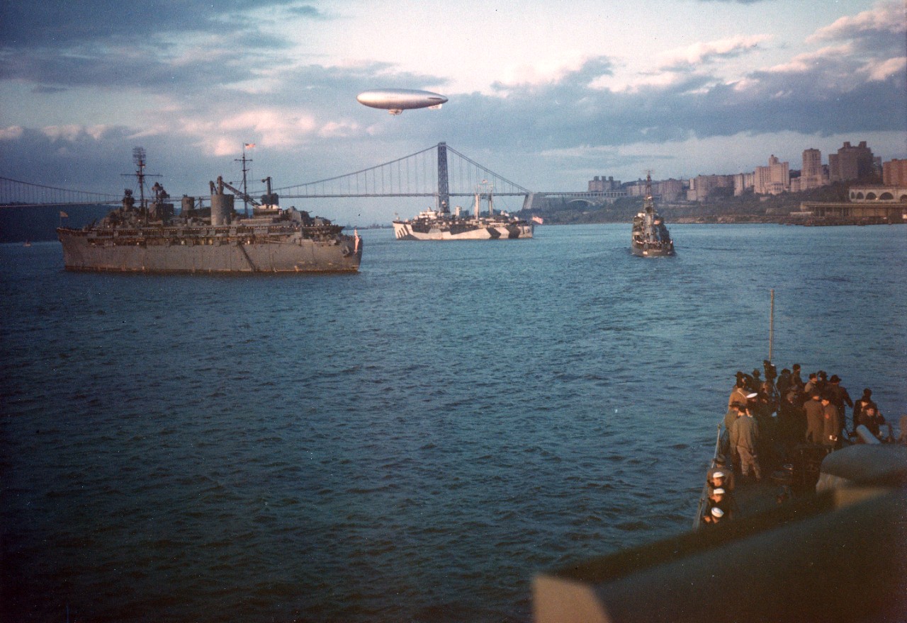 President Harry S. Truman, embarked on USS Renshaw (DD-499) in right center, steams up the Hudson River during his review of the fleet. Submarine tenders USS Orion (AS-19) and USS Howard W. Gilmore (AS-16) are at left and center, respectively. "K" type blimp is hovering overhead.