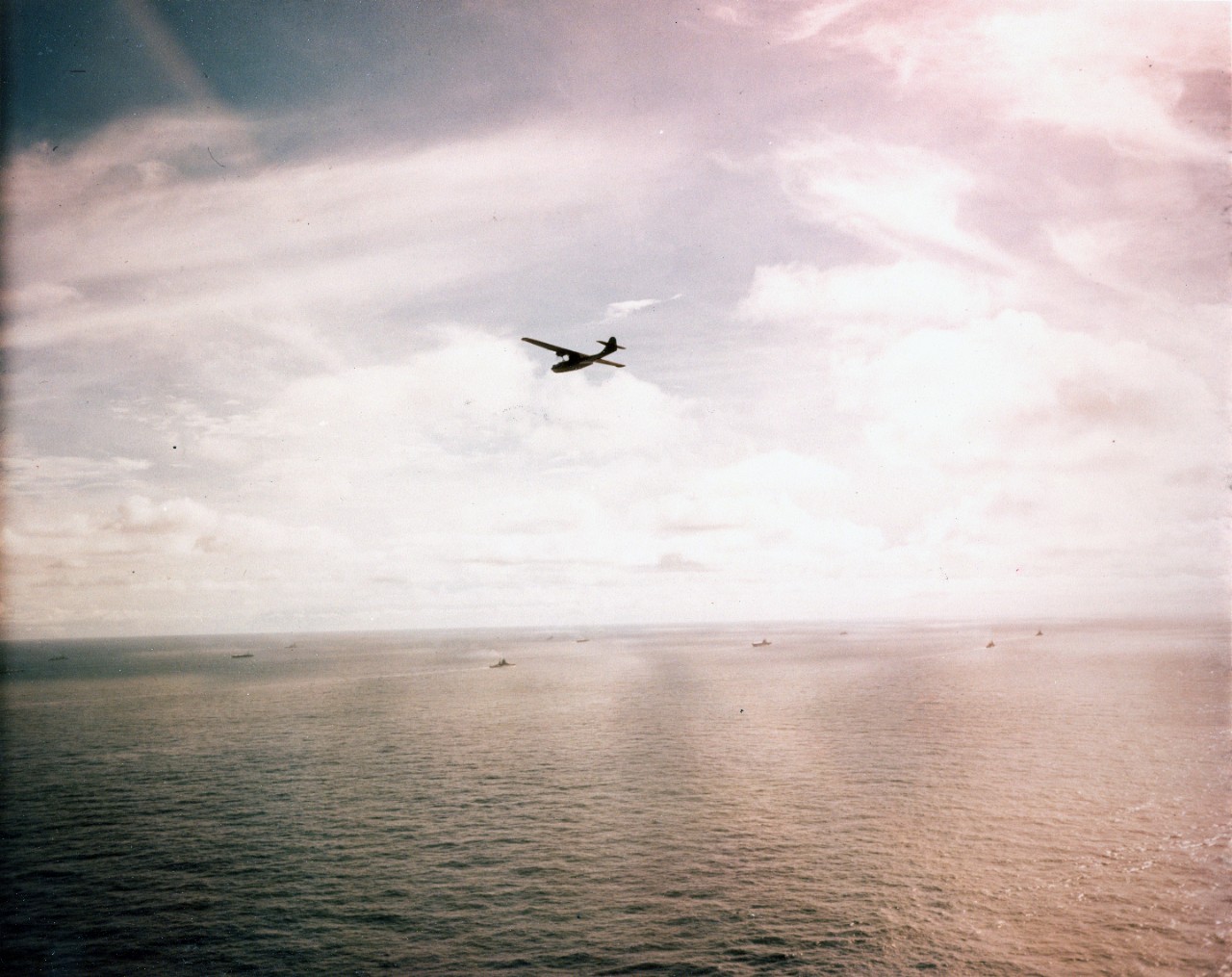 Consolidated PBY "Catalina" Patrol Bomber flies over warships steaming toward the Panama Canal, en route to the Atlantic Coast Navy Day Celebrations, October 1945.