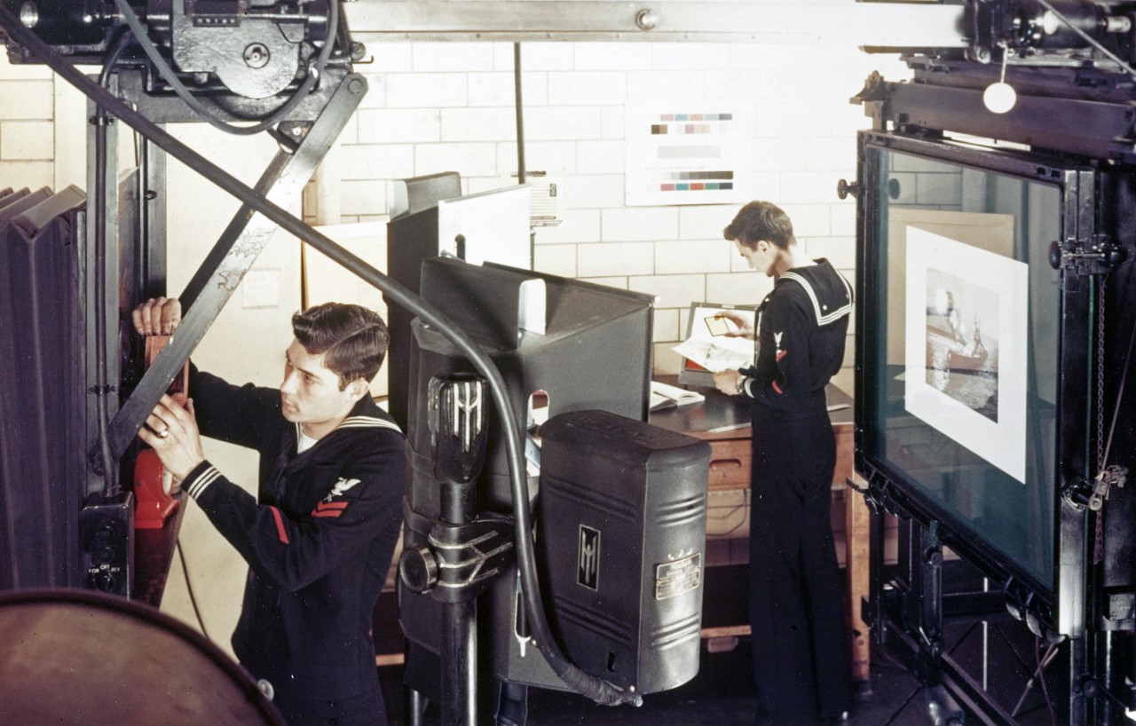 Large copy camera in use at the Naval Photographic Center's Graphic Arts Department, November 1951. Item lower center is a camera lamp made by the MacBeth Arc Lamp Co. Sailors wear rating badges of a Lithographer (left) and an Aviation Photographer's Mate.