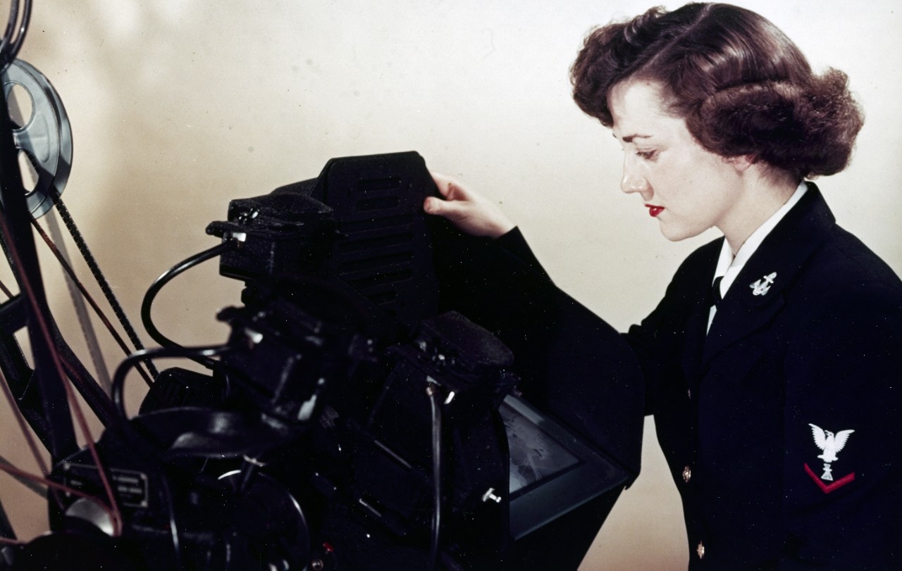 A WAVE Photographer's Mate screens motion picture film for editing, on a Moviola machine, in the Naval Photographic Center's motion picture editorial section, November 1951.