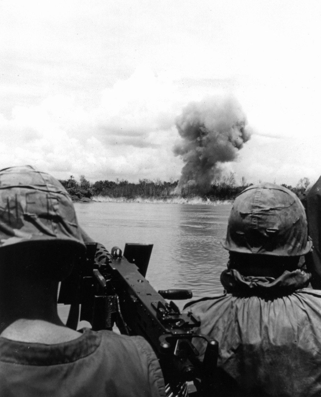 From a converted "Mike" boat on the Mekong River, which has picked them up following a search and destroy operation, Navy SEALs watch the detonation of a satchel charge they set to destroy a Viet Cong bunker, September 1967.