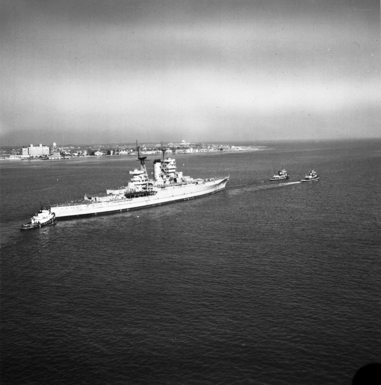 USS Mississippi (EAG-128) assisted by 3 tugs, leaves Hampton Roads for the last time, on 6 December 1956, en route to the scrapyard (Bethlehem Steel).