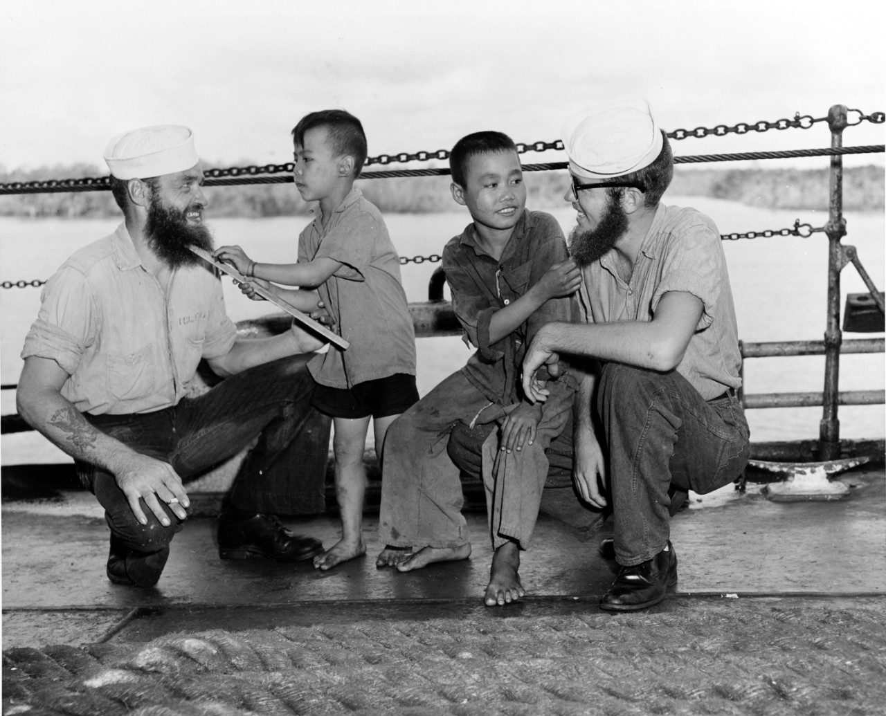 Contestants have their beards inspected by young Vietnamese refugees during the trip from Haiphong to Saigon, August 1954. ENS James I. Hart, USN (left), was declared the winner of the contest conducted among the sailors in the Indo-China area to operate "Passage to Freedom". 