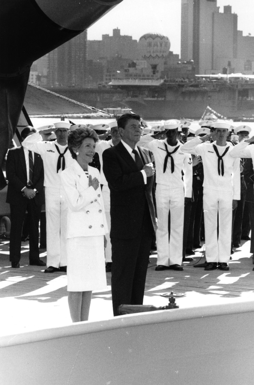 President and Mrs. Ronald Reagan and crewman on board the battleship USS Iowa (BB-61) honor the flag during celebrations commemorating Independence Day and the unveiling of the State of Liberty.