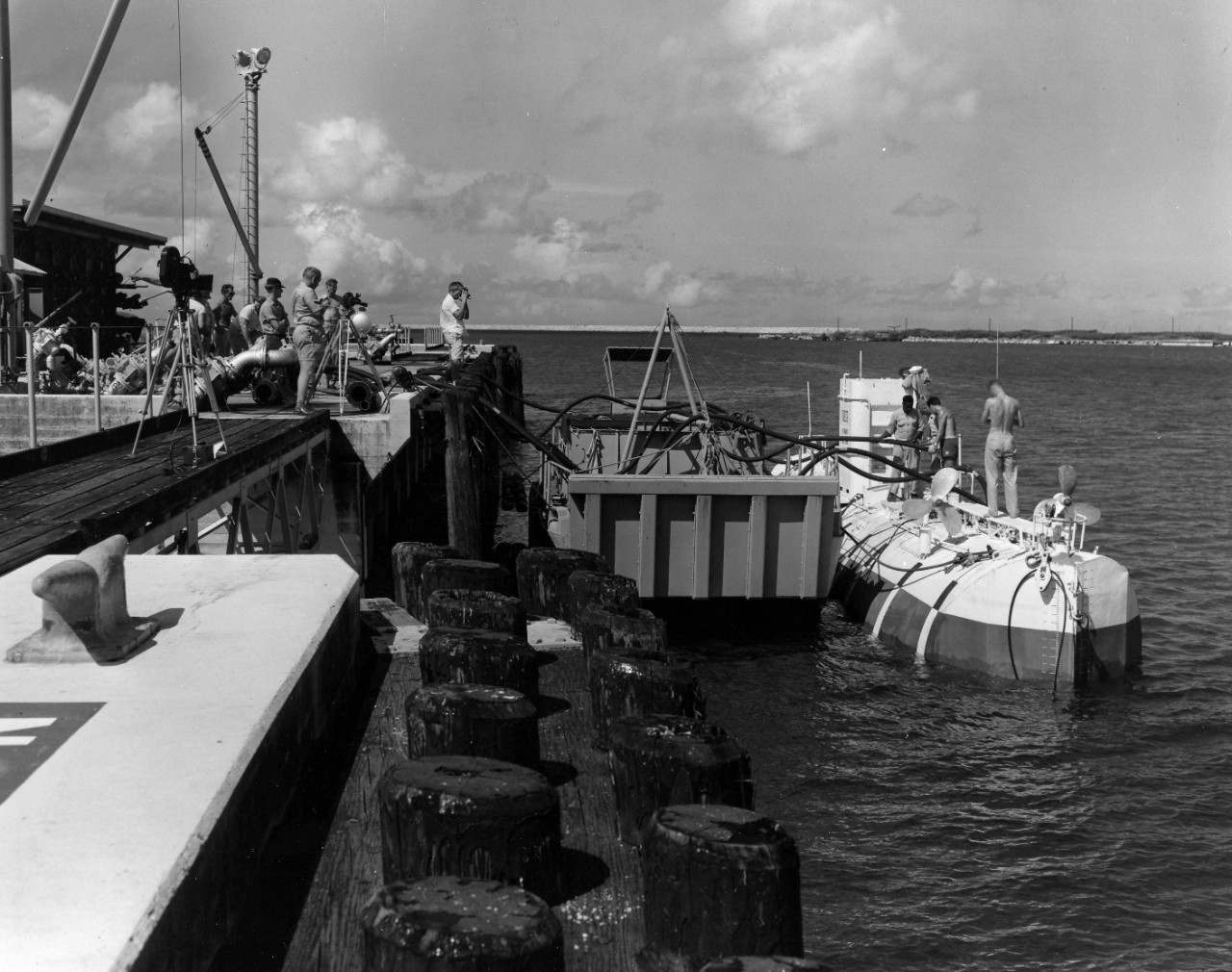 <p>Showing overall view of fueling operations at NSD Guam. LT Larry Shumacker on deck of Bathyscaph Trieste checking the depth of gas in the tanks. November 1959.</p>
