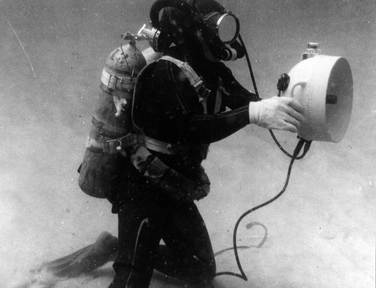 A Navy frogman tests new sonar equipment developed to located underwater objefcts. The light-weight, portable, diver-held sonar system is econmically powered by standard flashlight battering. Earphones provide the diver with audio information of objects by the searching sonar beam. May 5, 1960. 